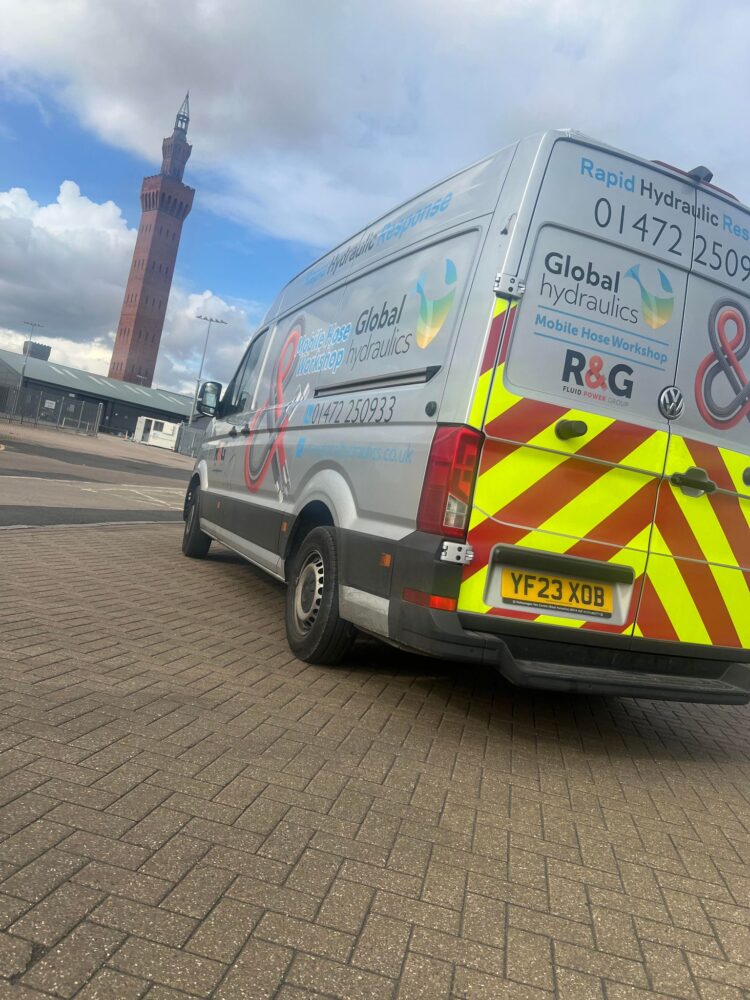 global hydraulics van on the pavement near a clock tower